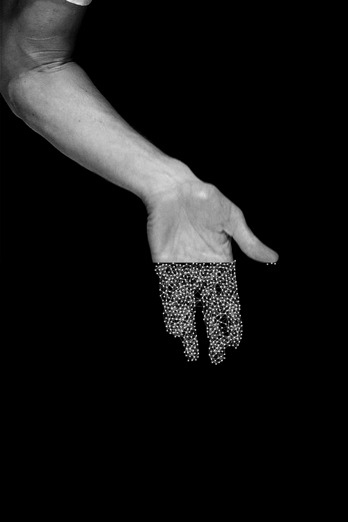 A human arm reaching down, fingertips dissolving into digital particles